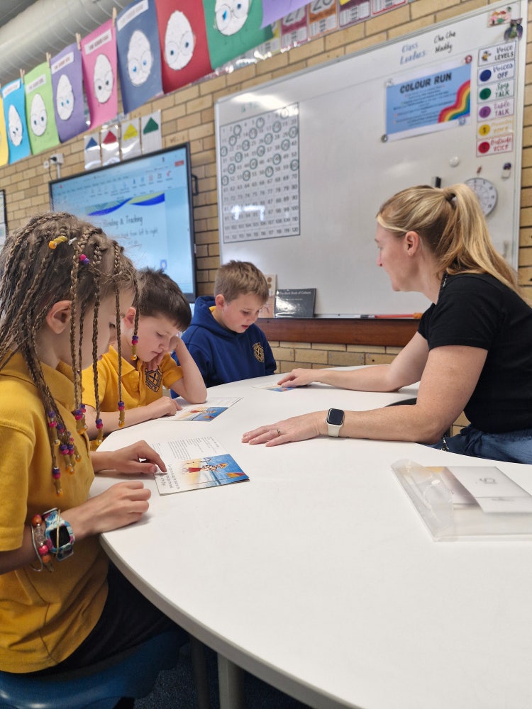SLSO with students at desk reading